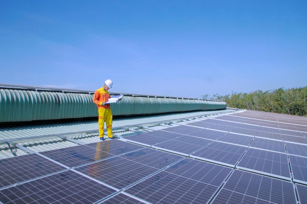Techniker prueft eine Photovoltaikanlage auf dem Dach